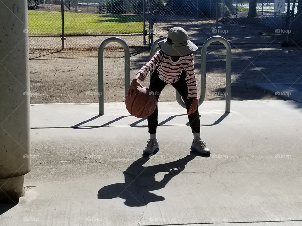 Boy dribbling basketball in a park