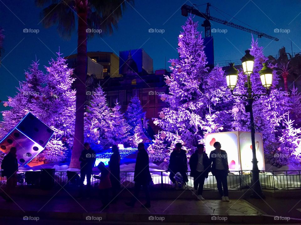 Purple Christmas city lights in Monaco Montecarlo with people silhouettes in the front; night at the Casino of Monaco Monte-Carlo 