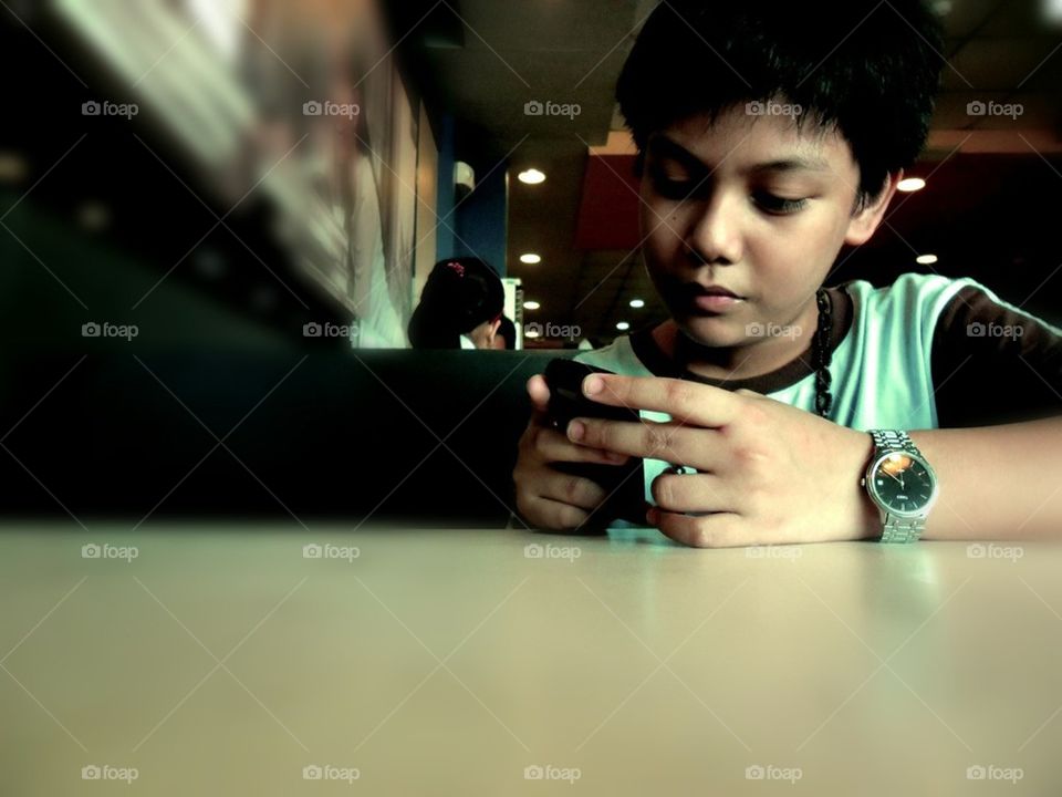 Boy teenager with a phone on a table