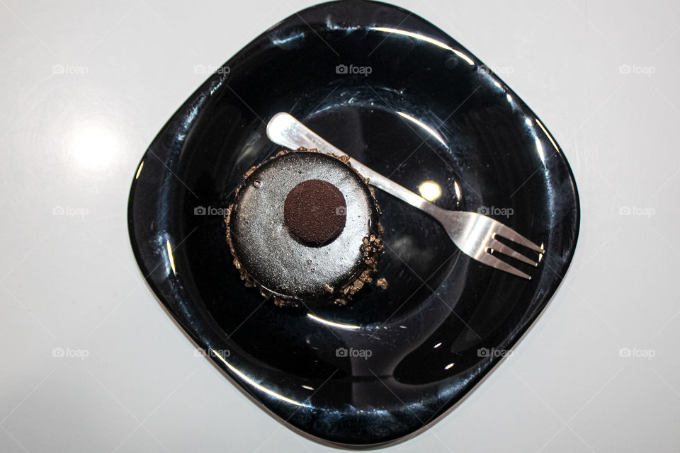 A chocolate cake with walnuts on a black plateA