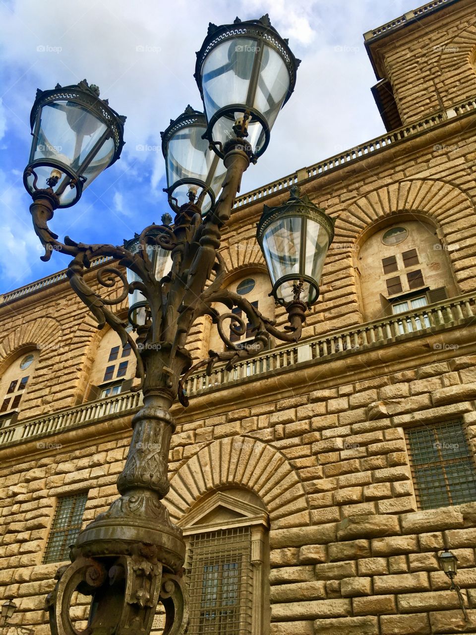 An ancient corner street lamp in beautiful Florence, Italy taken from below. The building is so vast and striking you just really have to pay attention to the details. 