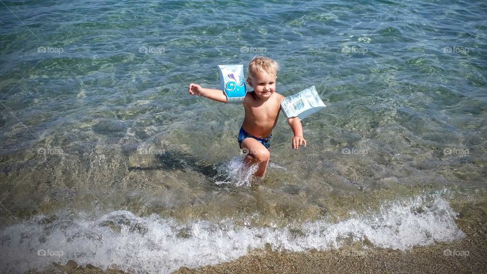 Little boy running up from water on beach
