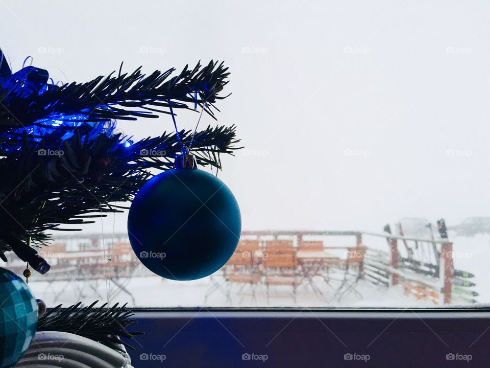 Blue Christmas globe hanging on the Christmas tree near the window