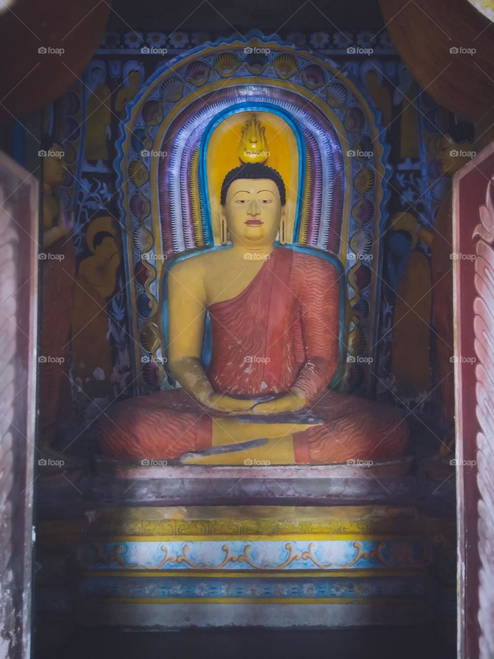 This is a capture of a statue of Load Buddha. Load buddha is the most sacred among Buddhists allover the world.This statue is situated in Sri Lanka and the coloured statue in a temple.The background is covered with shadows and the statue is clear.