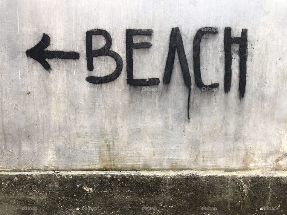 Super creepy beach sign. All caps, dripping, black paint. Arrow included. Bali, Indonesia. Taken August 2018.