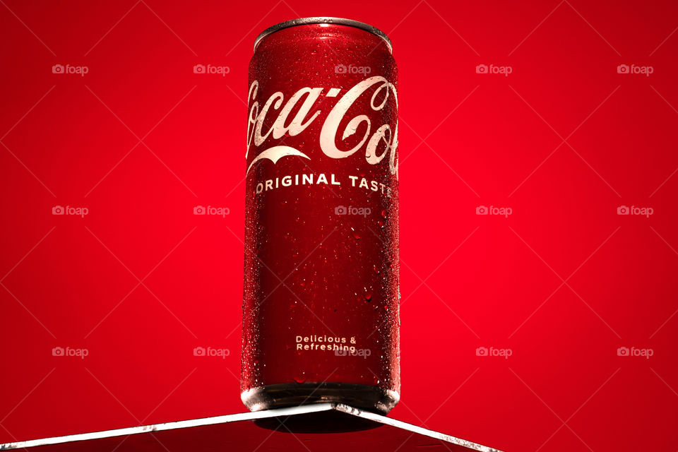 Coca cola on glass table. Red background