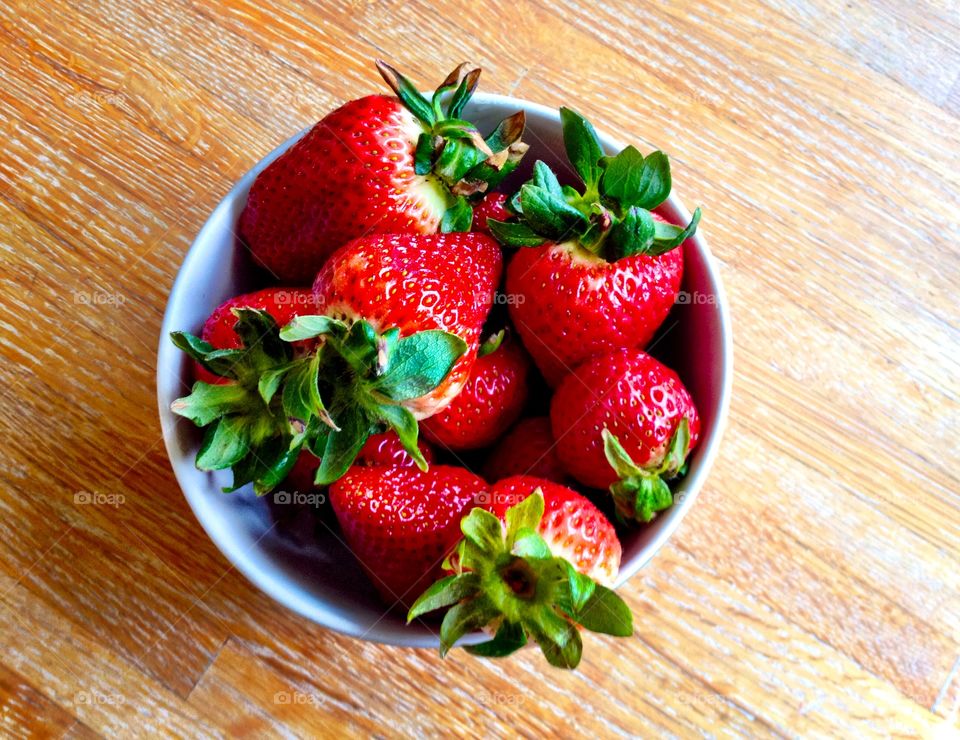 Bowl of strawberries. A bowl of big, ripe strawberries sitting in a wood table