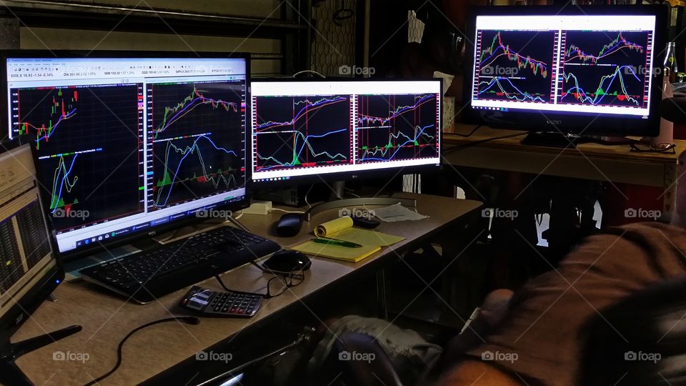 A man working on the stock market with several monitors and a computer