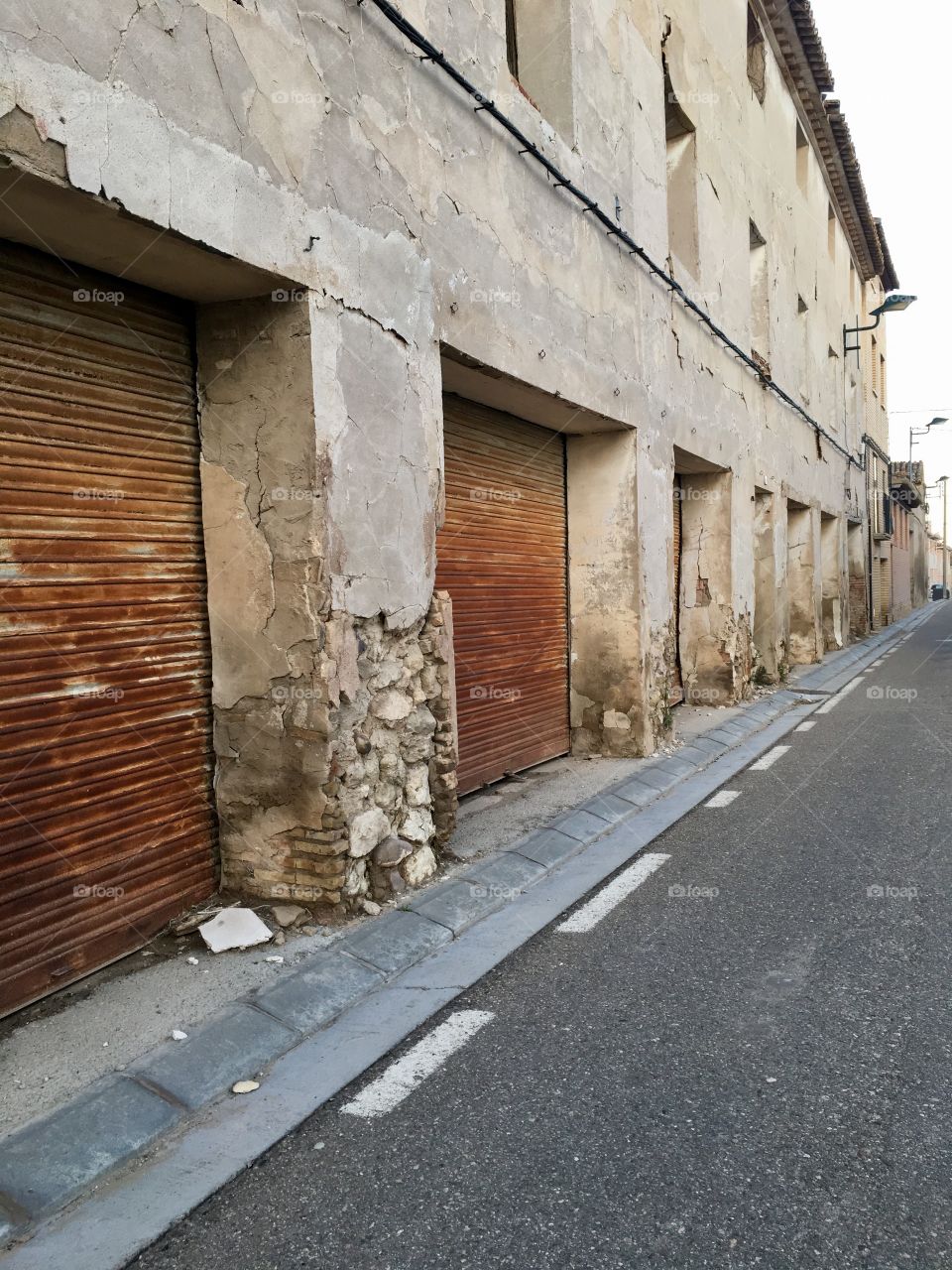A street in disrepair with rusted garages and crumbling walls. A village falling apart like so many towns and villages all over the world. 