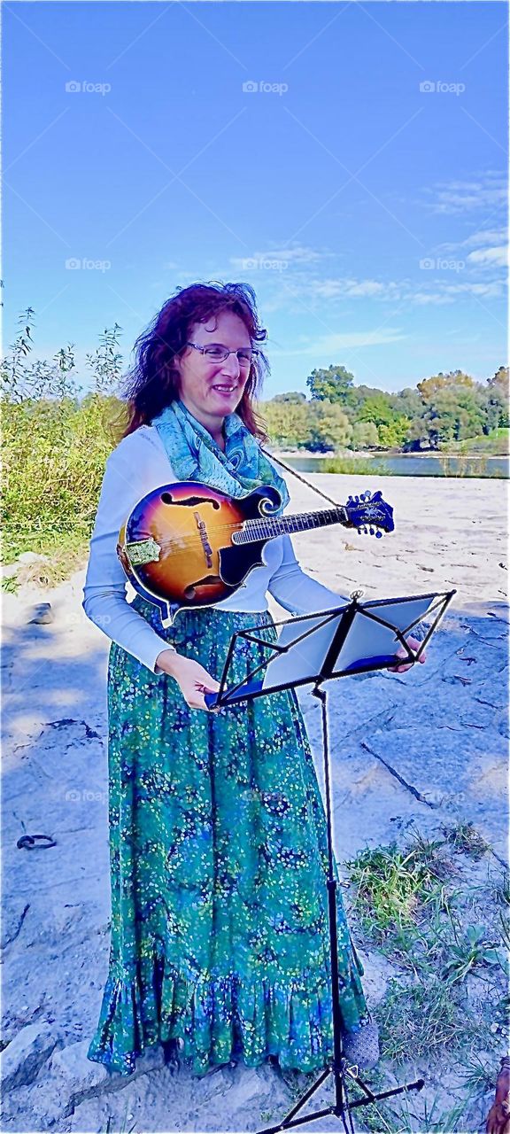 This lady loves music and her custom made instruments such as this antique style lute that she is displaying on a beautiful sunny Indian summer afternoon in „Bavaria“, Germany. 2023. Hypnotic Productions