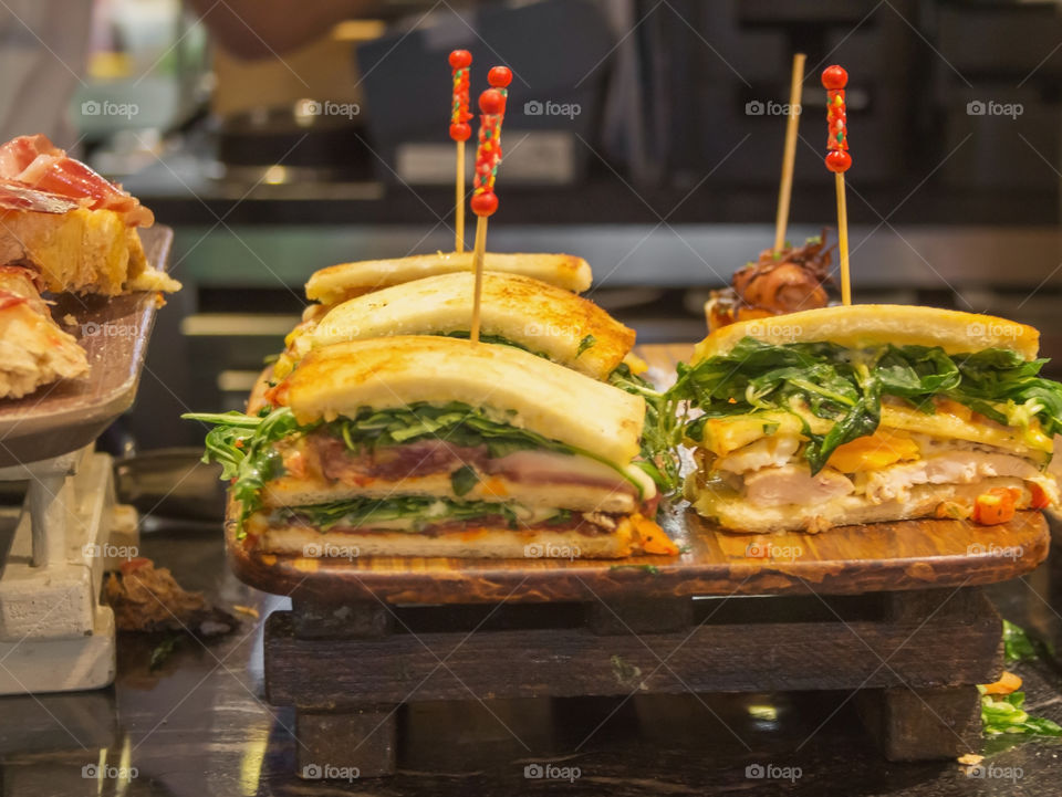 Spanish pinchoses with meat,cheese and greens lie on a stylish wooden showcase in restaurant