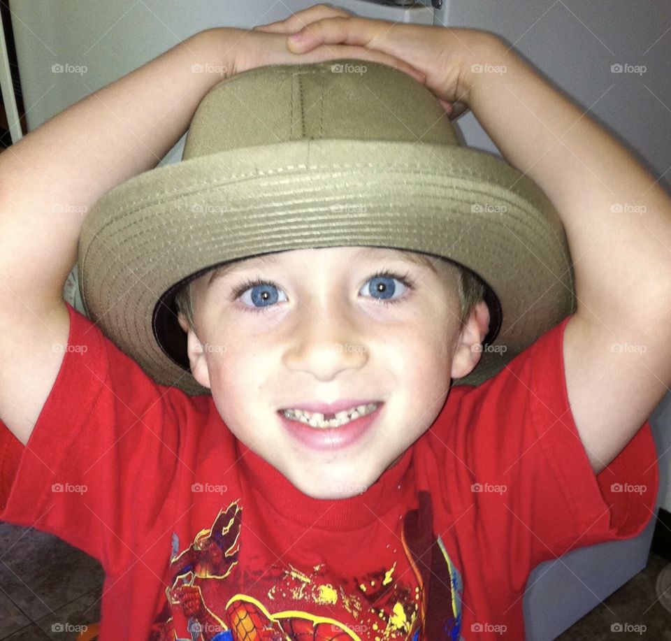 Little boy wearing a hat and a red t-shirt, boy has bright blue eyes