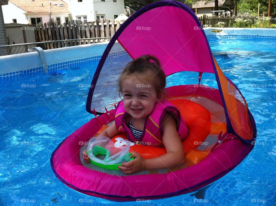 Sweet Swimmer . Toddler girl, floating in a pool in the summertime. 