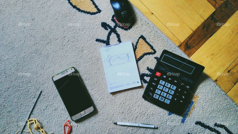 calculator, notebook, smartphone, mouse and pen are lying on the floor