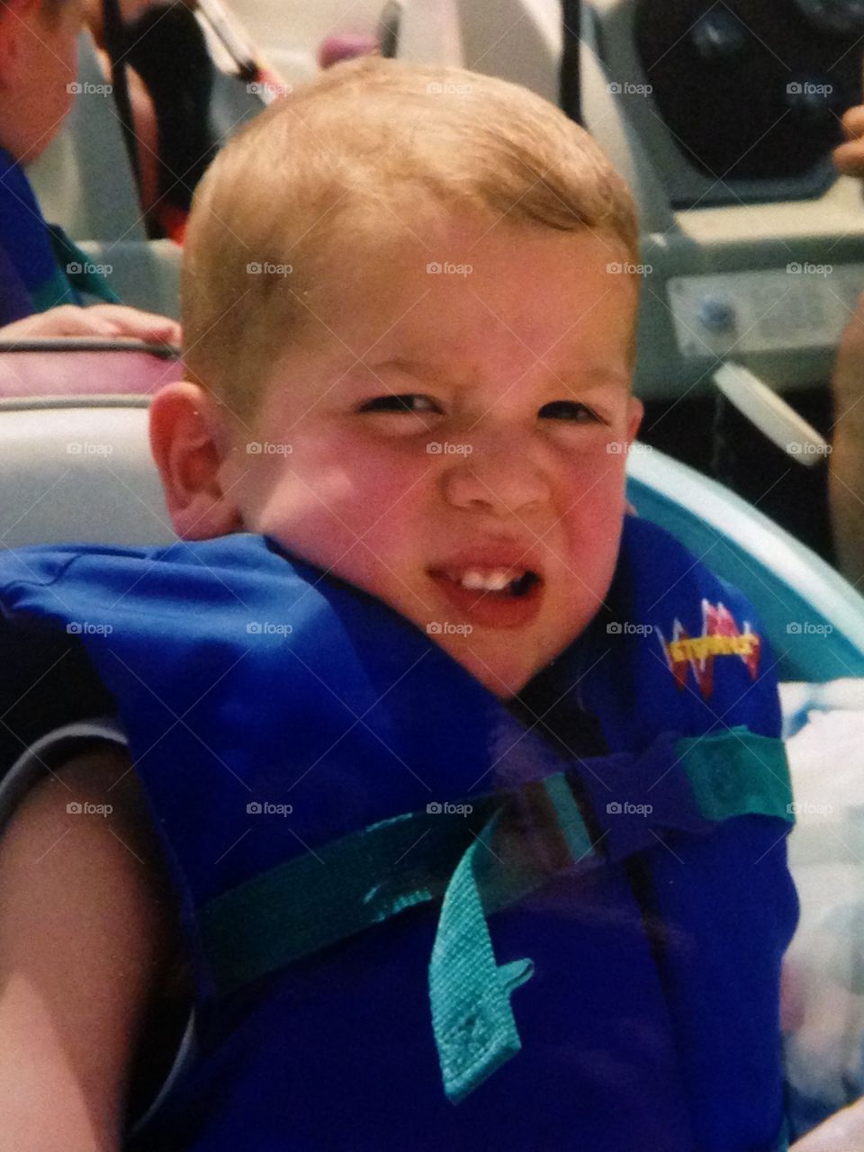 Sunburnt face boy on boat wearing life vest 