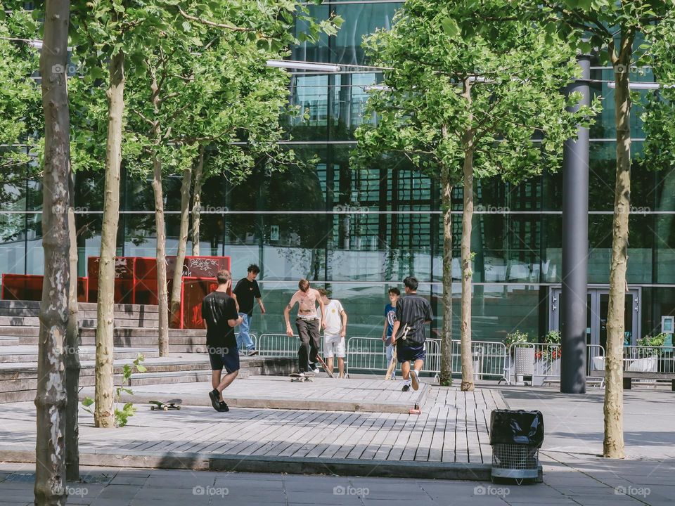 A group of young boys and teenagers skateboarding in a city park on a summer sunny day in Luxembourg, close-up side view. Concept summer in the city.