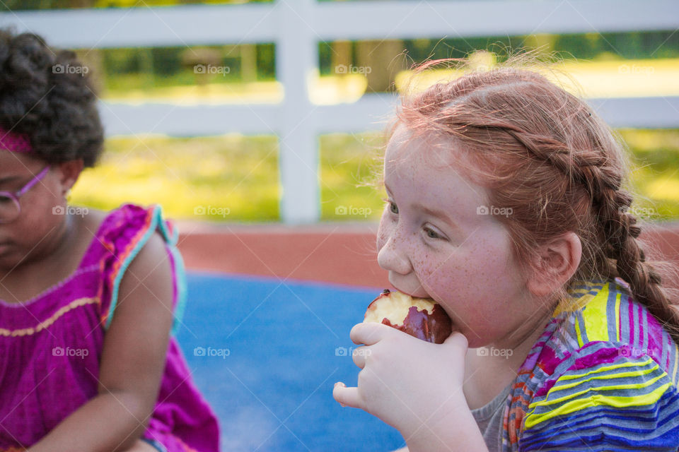 Young Girl Eating an Apple at the Park