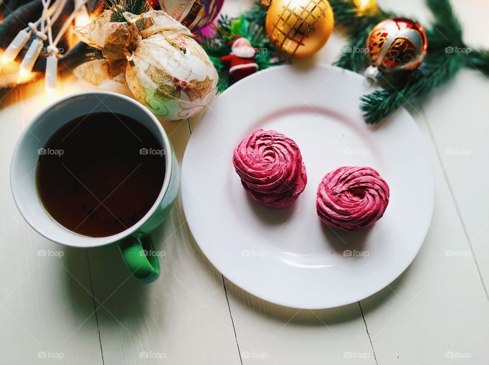 Christmas toys, a cup of hot tea, marshmallows and Christmas decorations on a white table