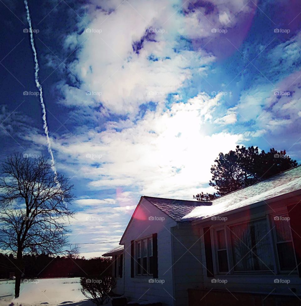 blue sky with white clouds reflecting small amounts of purple and green.