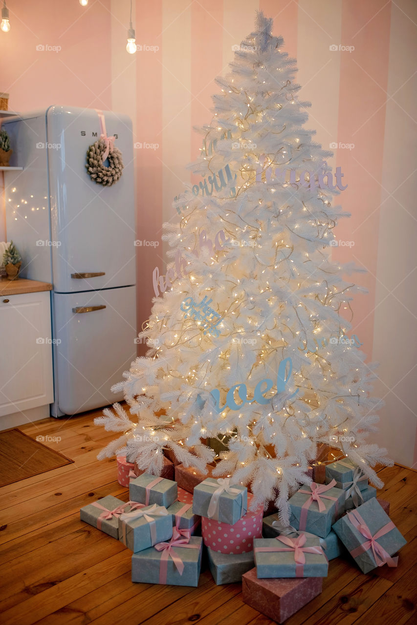 Festive winter cozy kitchen interior with garlands, decorations and gifts.  Christmas dinner at the decorated table.