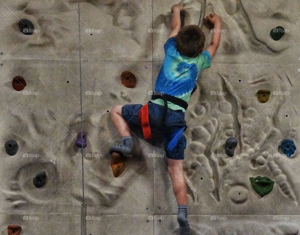 Young Rock Climber. Boy Scaling A Rock Wall
