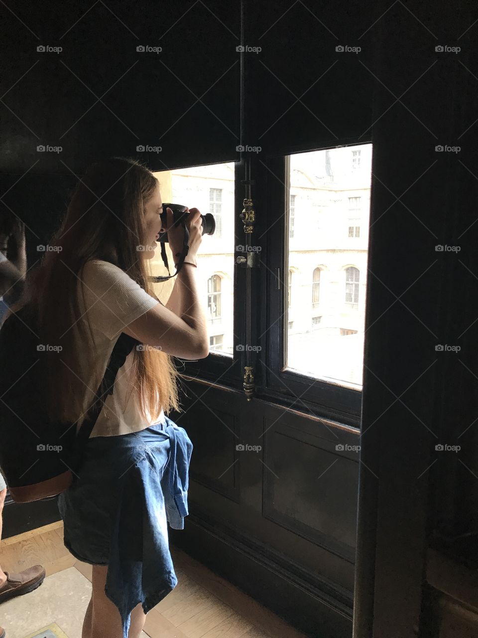 Woman taking photograph with camera from glass window