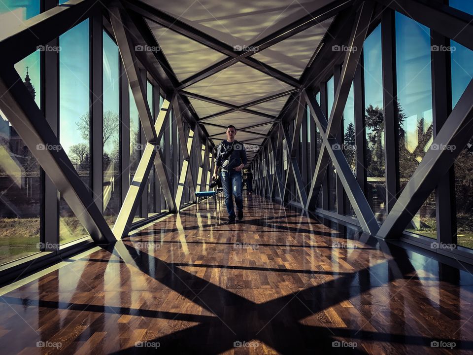 Male photographer with camera walking on footbridge 