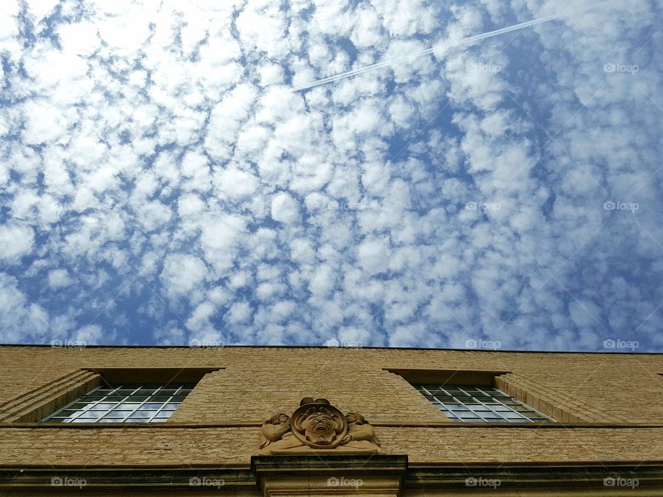 White Fluffy Clouds in a Blue Sky above a Stone Building