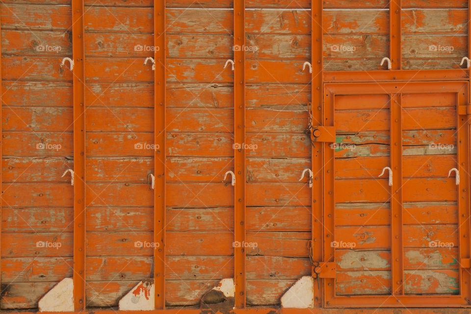 Closeup abstract of an orange textured wooden paneled truck outside of Meknes, Morocco, North Africa.