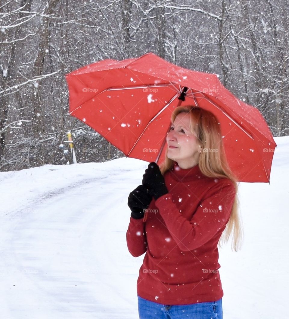 Woman with red Totes umbrella during a snow storm 