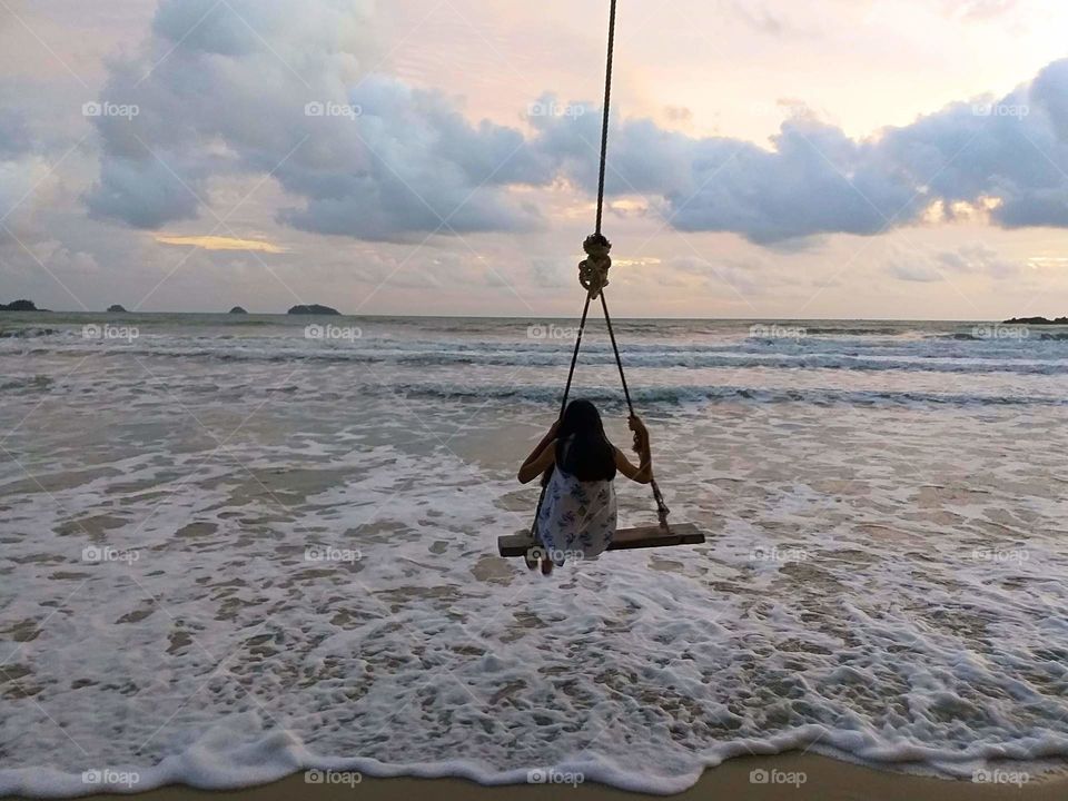 girl playing swing on the beach. dream vacation.