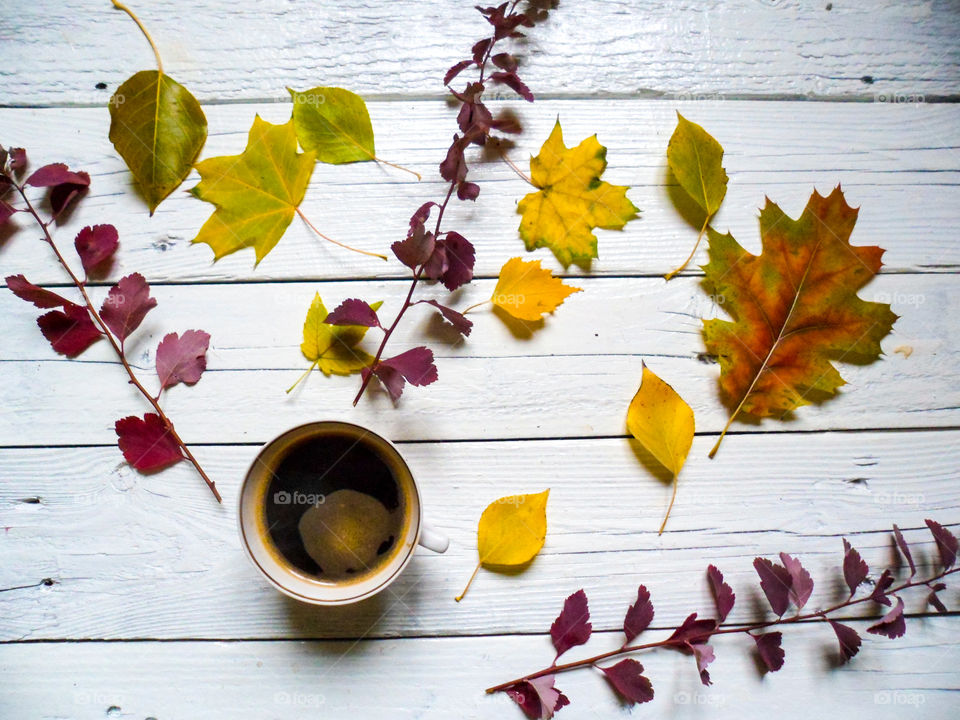 Coffee cup and autumn leaves on table