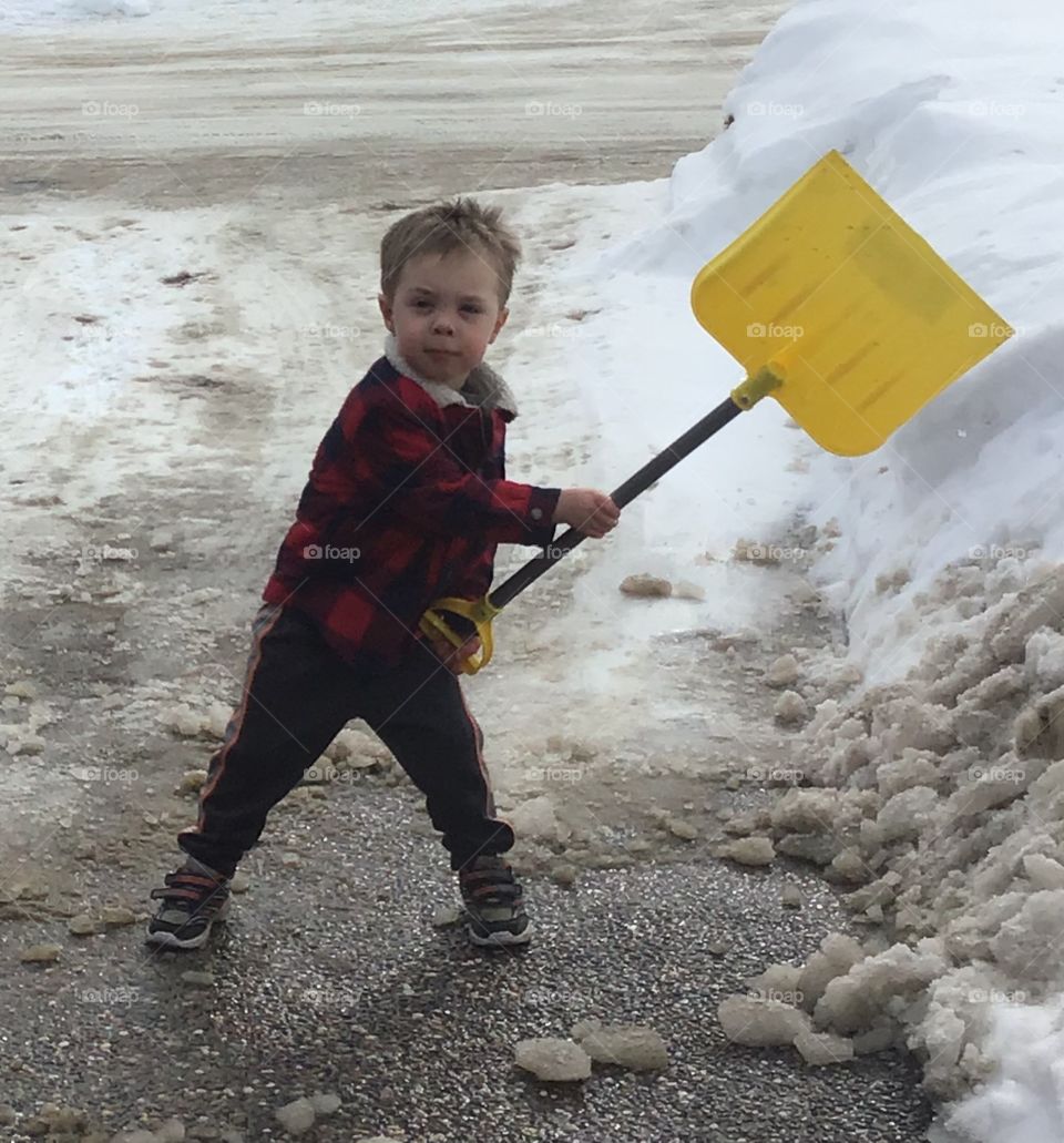 Little boy shoveling the driveway 