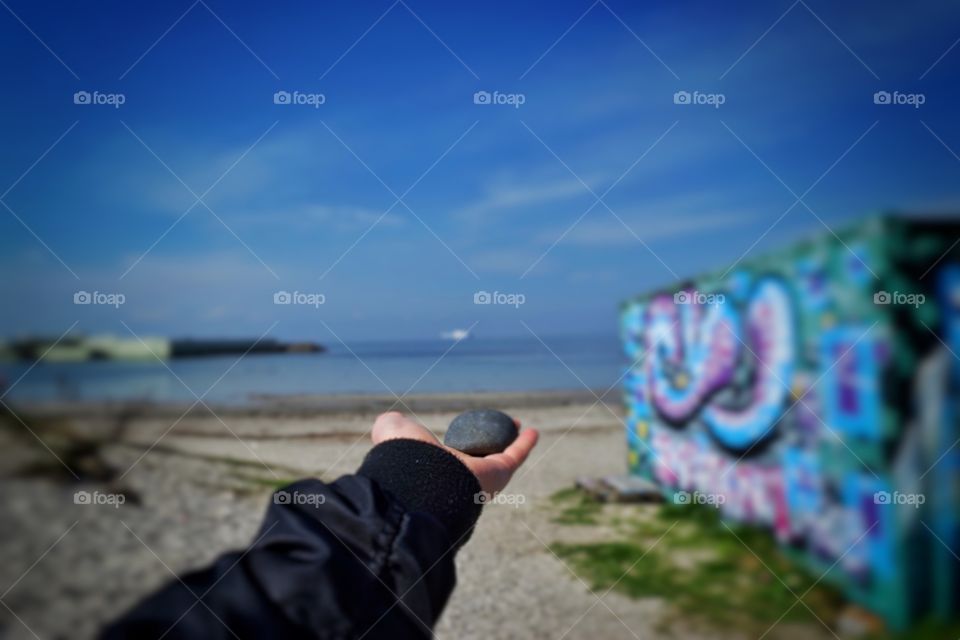 Stone in hand with sea in background