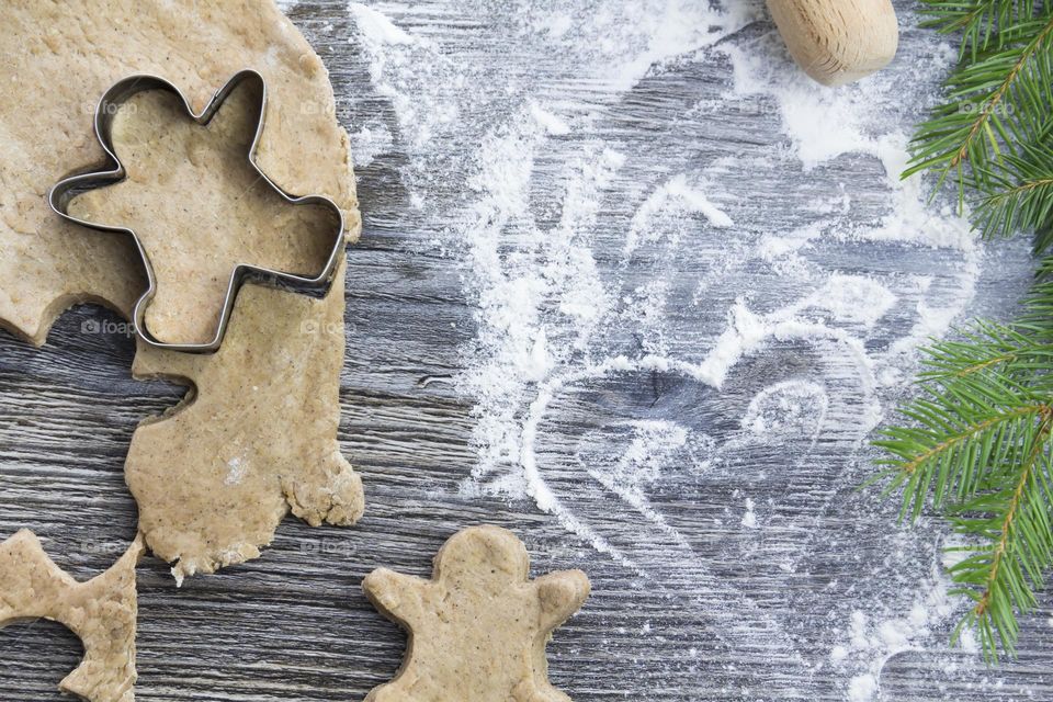 Cooking Christmas gingerbread cookies on a wooden table with tangerines and green Christmas trees.