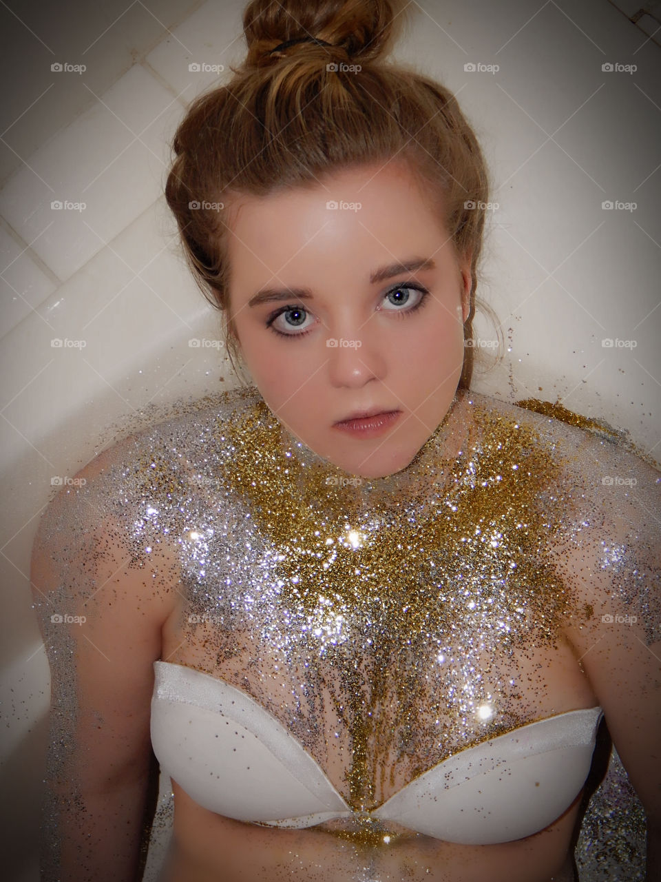 Beautiful girl with gold glitter in bathtub