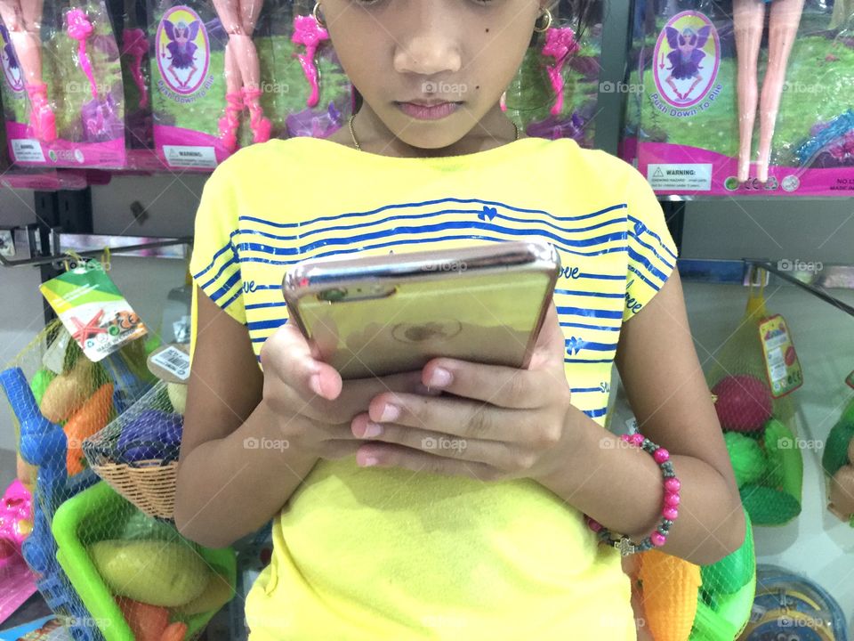 A little girl using phone at the mall