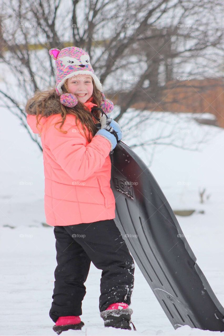 Portrait of a girl holding sled during winter