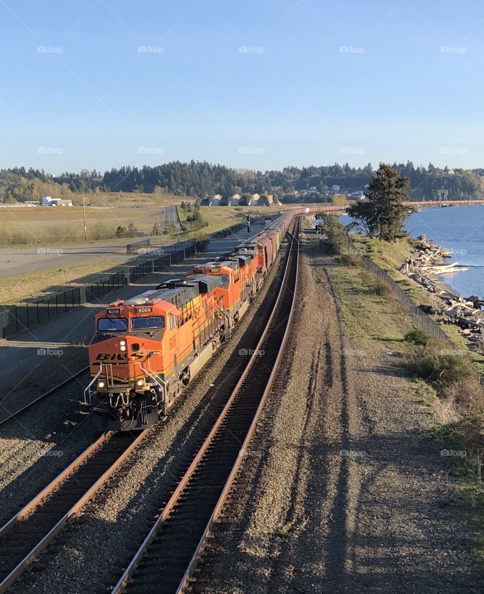 Orange freight train traveling along the waterfront 