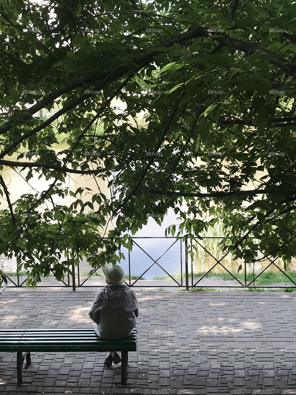 Senior woman enjoying last summer days on the bench near the lake 