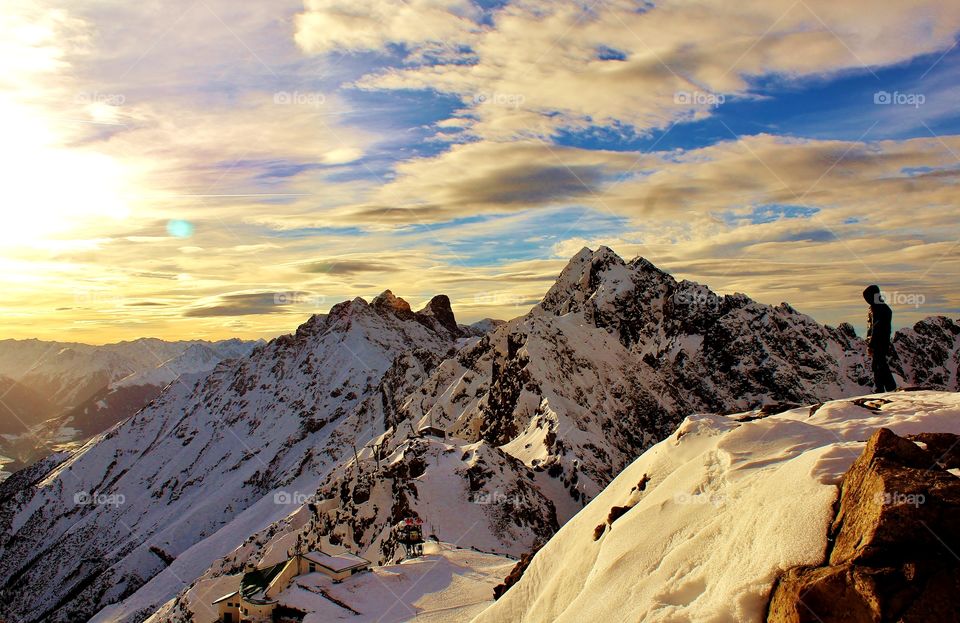 Hiker standing on snowy mountain at sunset