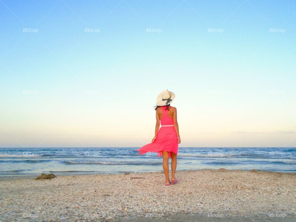 Rear view of a woman with hat walking at beach