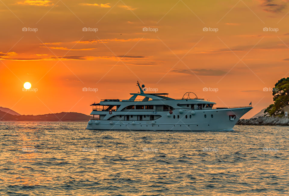 Ship sailing at sunset