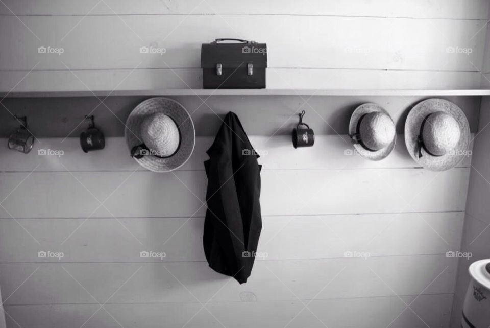 Simple life. Entrance way into an Amish home , hats hang on wall , a cup , shelf , jacket , accessories of a home.