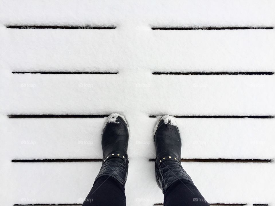 Looking down at black woman's boots on snow