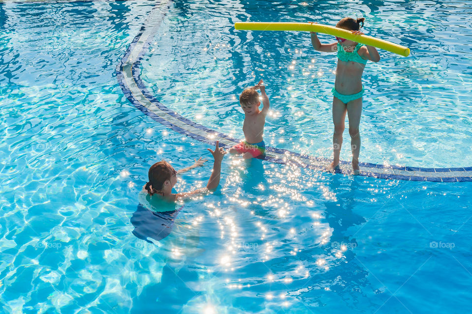 Mom encouraging little boy to take a dive into the swimming pool. Learning how to swim.