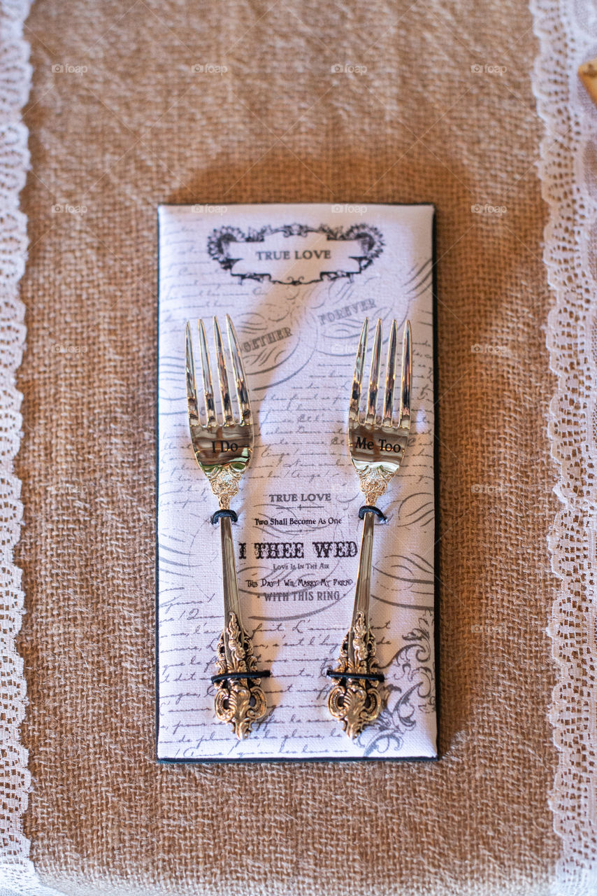 Two gold forks on text napkins on canvass table
