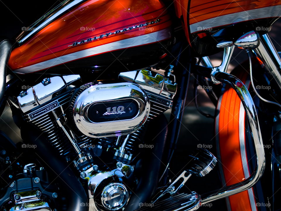 A magnificent bright orange Harley Davidson motorcycle with lots of shiny chrome. 