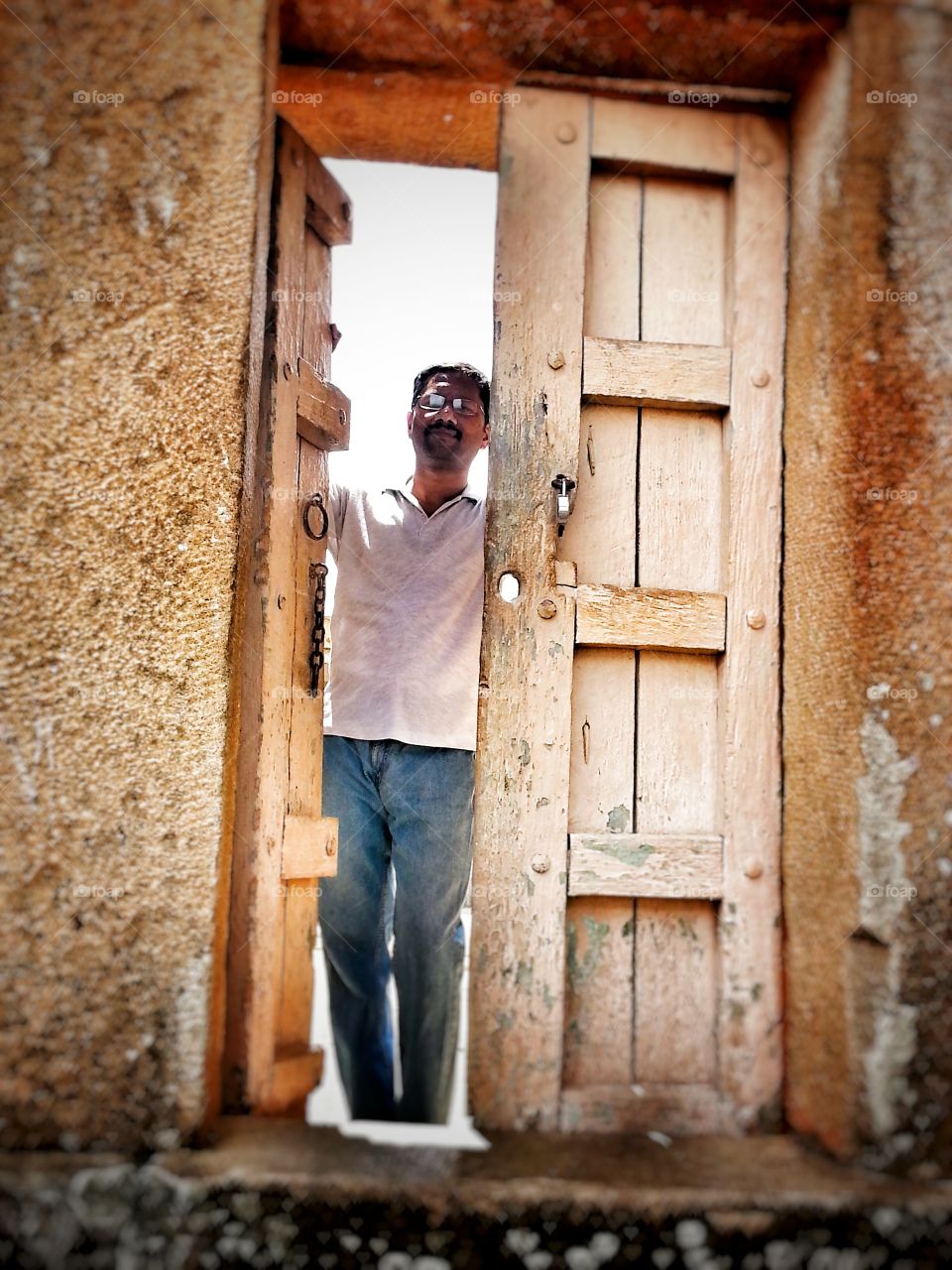 Man standing near old wooden door of a house