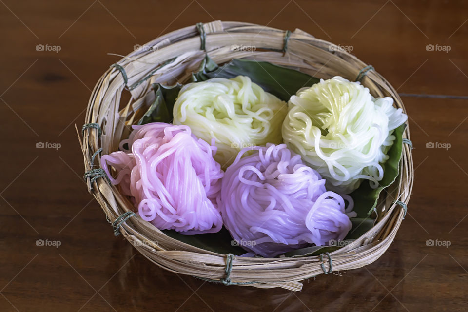 Colorful rice noodles on a banana leaf In a bamboo basket on the table.